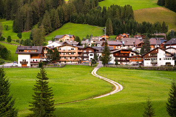 Mountain village with a church in Dolomite alps in summer among green meadows