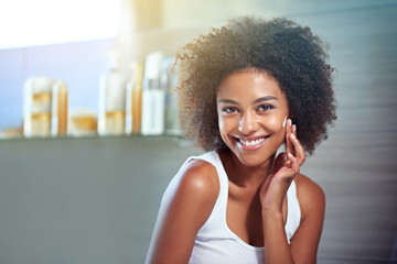 African woman, portrait and facial cream with smile, wellness or afro in home bathroom for morning...