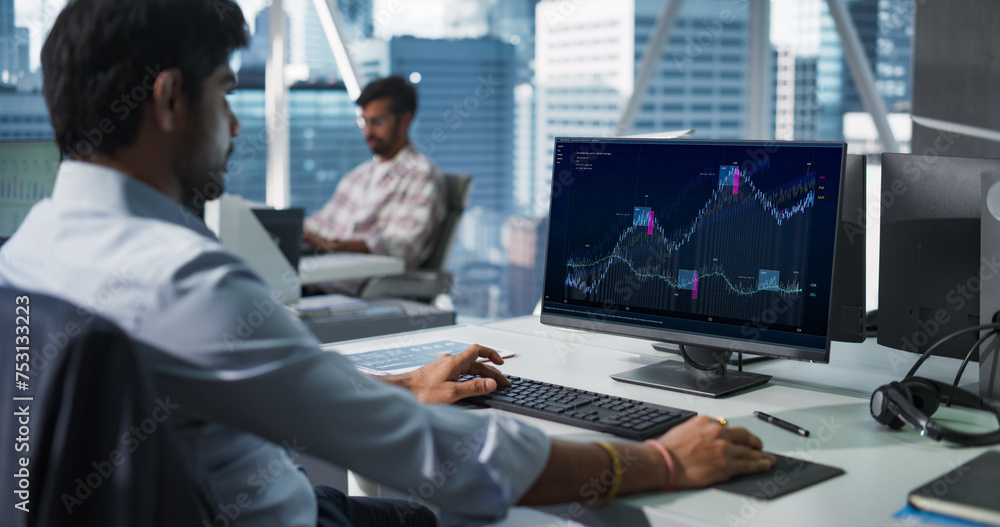 Poster Hedge Fund Office: Indian Financial Analyst Using Computer with Display Showing Real-Time Stocks, Exchange Market Charts. Hard Working South Asian Trader Making Profitable Investment.