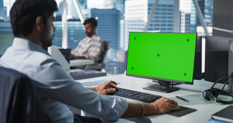 Indian Chief Financial Officer Working on Desktop Computer with Green Screen Mock Up Display. Young South Asian Specialist Analyzing Corporate Banking Account, Researching Investment Opportunities