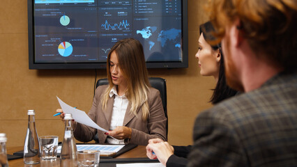 A diverse multinational team of professional business people meet in the conference room of a modern office. Creative team at the table discussing data analysis and planning a marketing campaign