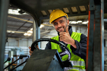 forklift driver sits in his vehicle in a warehouse and gives a thumbs up to show confidence in his...