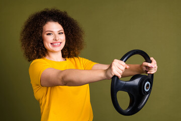 Photo of young beautiful curly hair lady in yellow t shirt riding automobile test drive simulator...