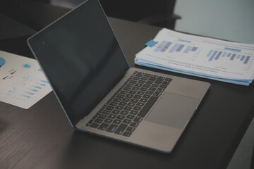 Laptop on a desk in an open financial office.