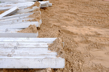 The construction site is covered with sand.Concrete piles or pillars. The construction of a monolithic building or bridge has begun.Preparation for the construction of the facility.Sandy embankment.