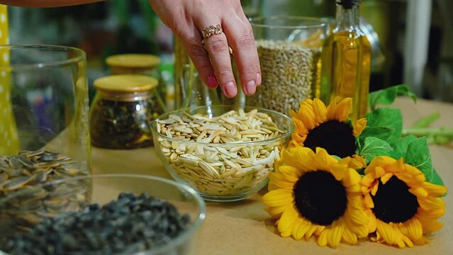 Sunflower products, close-up, a woman hand touches the seeds. eco friendly food, healthy eating concept, background. Various types of sunflower seeds, tea, cookies, butter and sunflower flowers.