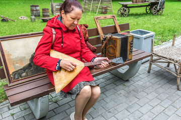 A woman is playing the balalaika in a city park