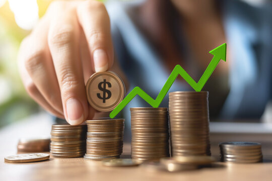 A woman counts coins in stacks with a dollar sign. Above them is a green arrow showing increase. The concept of increase in profits, rate, dividends, interest. Saving money for the future. Finance, in