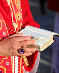 Hand of elderly priest wearing large ring holding Bible