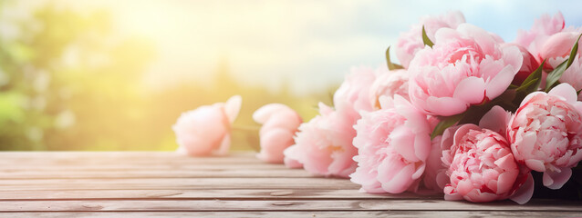 Beautiful bunch of pink peony on wooden planks table outdoors in a sunny day