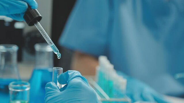 Doctor hand taking a blood sample tube from a rack with machines of analysis in the lab background, Technician holding blood tube test in the research laboratory.
