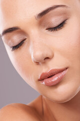Obraz premium Woman, studio and thinking with dreaming, cosmetics and gloss for makeup and glamour appeal in face zoom. Female person, eyebrow and micro blading for lipstick, foundation and grey background beauty