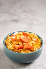 Bowl of corn flakes with sliced strawberries.