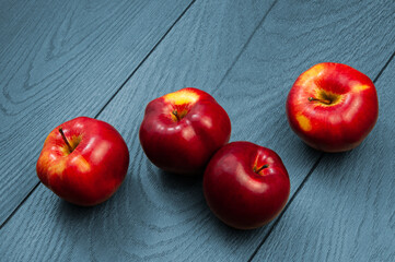 red ripe apples on a blue wooden background.