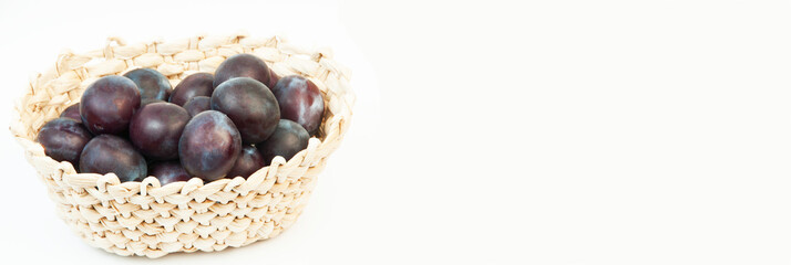 round blue plums in a basket on a white background. ripe sweet plums on a light texture	