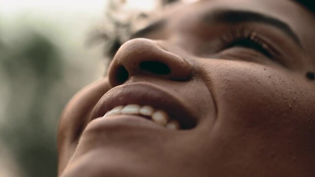 Happy Spiritual Young African American Woman gazing Skywards feeling the presence of GOD, macro close-up face with wide grin