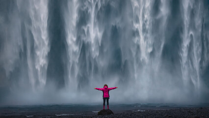 Women standing close to huge waterfall as tourist attraction