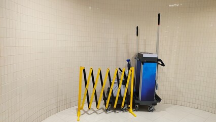 Various cleaning equipment like brush, mop and spray on the floor near clean airport bathroom or...