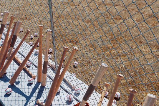 Picture of baseball bats leaning against the fence around the baseball field