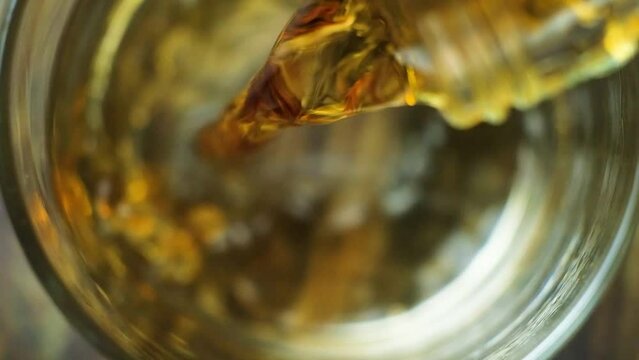 Process of pouring cognac from glass bottle macro slow motion top view