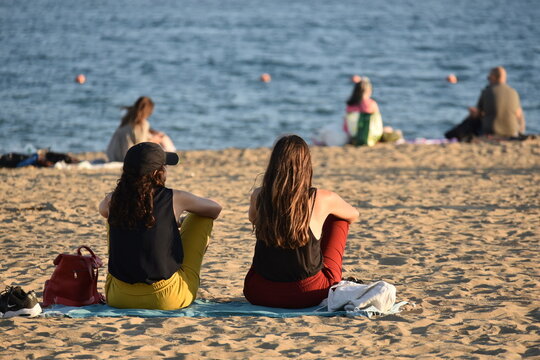 Two ladies sit and talk on a beach in Spain