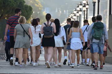 A large group of teenagers walk through Plaça d'Espanya as dusk approaches