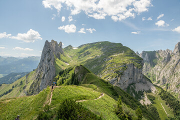 Some hikers hiking towards Saxer Lücke in Alpstein mountains in Switzerland during summer. Beautiful hike from  Hohen Kasten toward the beautiful rock formation Saxer Lücke. Beautiful Swiss Alps.