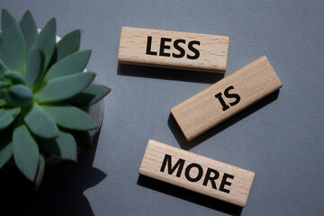 Less is More symbol. Concept words Less is More on wooden blocks. Beautiful grey background with...