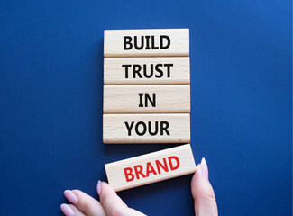 Build trust in your brand symbol. Wooden blocks with words Build trust in your brand. Beautiful deep blue background. Businessman hand. Business and Build trust in your brand concept. Copy space.
