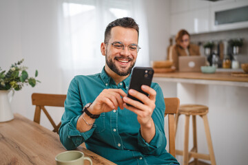 man with eyeglasses stand at home use mobile phone sms texting