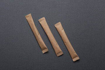 Packages of single-serve coffee or sugar on dark gray background