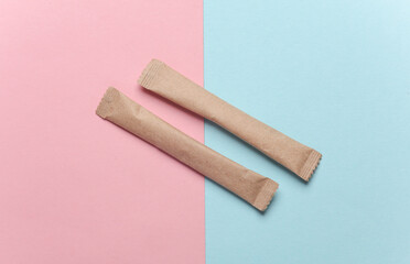 Packages of single-serve coffee or sugar on pink blue background