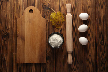 wooden kitchen board, rolling pin, eggs and flour on a wooden table. Cooking, culinary, baking....