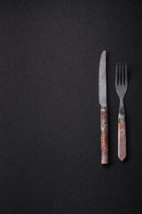 Cutlery fork, knife and spoon on a dark textured concrete background