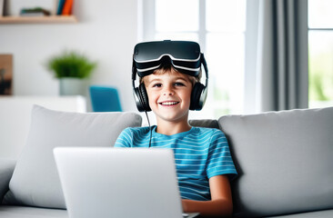 Fototapeta na wymiar 10 yo boy sitting at sofa, VR garniture on his head, opened laptop. Child interacts with virtual characters in virtual reality, bright childrens room blurred background. Play, communication, education
