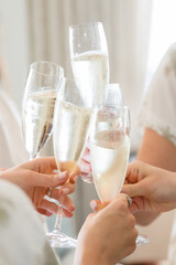 bride and bridesmaids toasting with champagne flutes. Bright and cheerful vertical color photograph close crop no faces