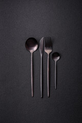 Cutlery fork, knife and spoon on a dark textured concrete background