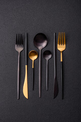 Cutlery fork, knife and spoon on a dark textured concrete background