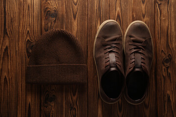 Used leather sneakers and hat on a wooden background