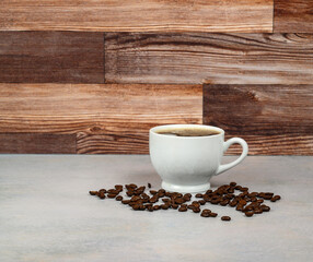 Coffee in white porcelain cup surrounded by coffee beans 