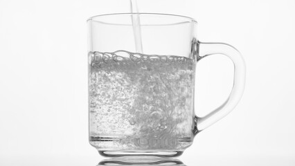 Pouring drink water to glass, white background. Glass with fresh clean drinking water