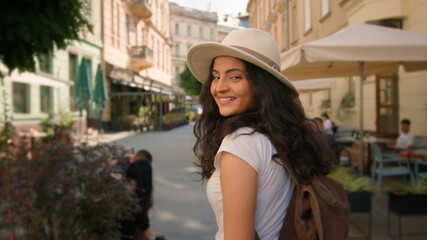 Walking outdoor cheerful smiling stylish Indian Arabian woman lady female tourist traveler follows...