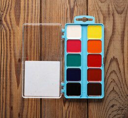 Palette of watercolor paints on a wooden table