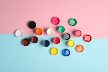 Set of gouache paint in bottles on a blue-pink background