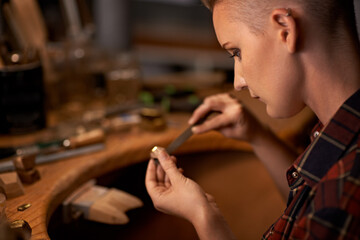 Woodworking, tools and artist in workshop with creative project or sculpture on table at night. Artisan, carpenter and woman with talent for creativity in dark studio in process of carving wood