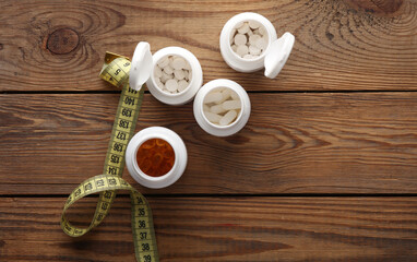 Weight loss concept. Pills bottles and measuring tape on floor. Top view