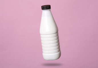 Yogurt bottle levitates on a pink background with a shadow