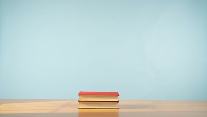 Two books on a wooden table on a soothing pastel blue background.