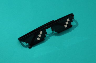 8 bit pixel sunglasses on blue background with a shadow. Minimalism style.