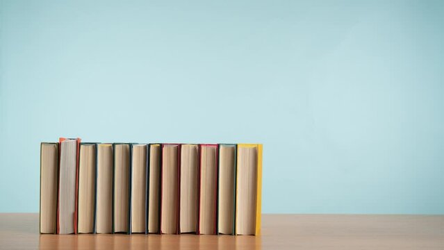 Stop Motion Of Colorful Old Books Being Moved From A Stack To A Row And Back Again On A Wooden Table